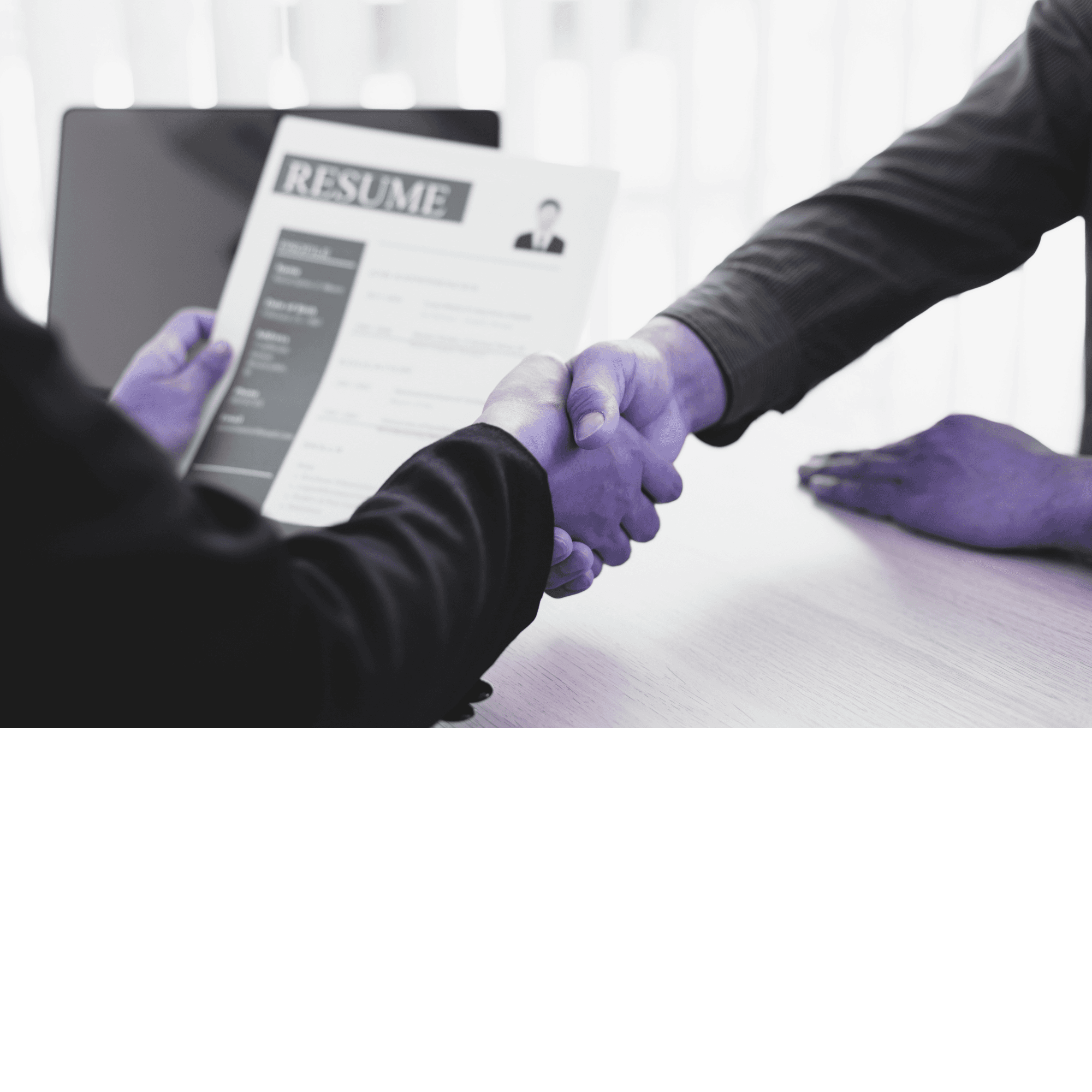 Two professionals shaking hands over a desk with a resume document
